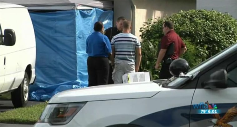 Investigators gather at the scene the bodies of two teens were found in an SUV parked in a garage.