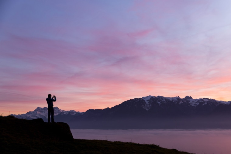 Image: A man takes a picture of the sea of fog that covers Geneva Lake