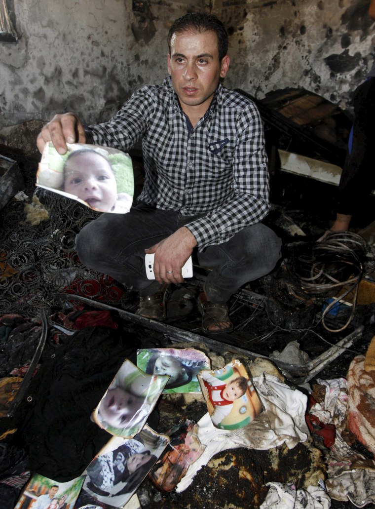 Image: Relative of 18-month-old Palestinian baby Ali Dawabsheh, who was killed after his family's house was set to fire in a suspected attack by Jewish extremists, shows his picture at the burnt house in Duma village near the West Bank city of Nablus