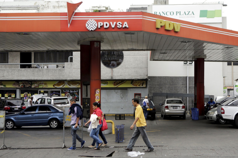 Image: People walk past a gas station of Venezuela's oil company PDVSA in Caracas