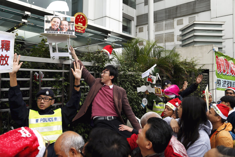 Image: A pro-democracy demonstrator holds up prop with a photo of Liu and his wife Liu Xia