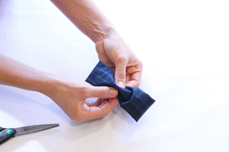 With your last fabric strip, fold a 1” long piece into a clean ribbon by folding raw edges towards each other. Hot glue onto the middle of the bowtie to secure together.