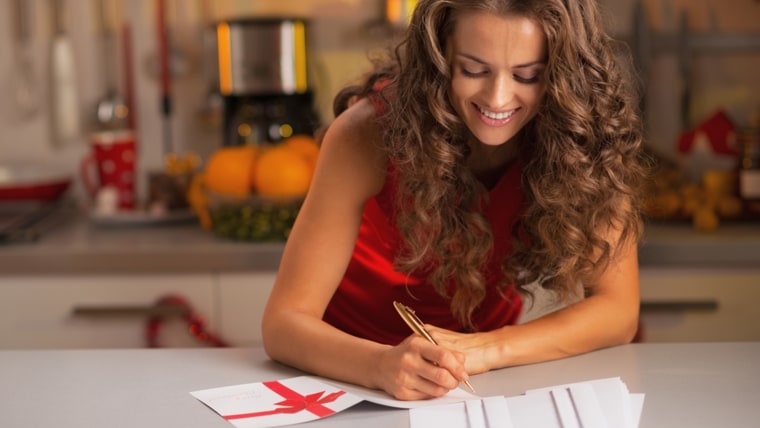 Happy young housewife signing christmas postcards in kitchen; Shutterstock ID 158618495; PO: TODAY.com