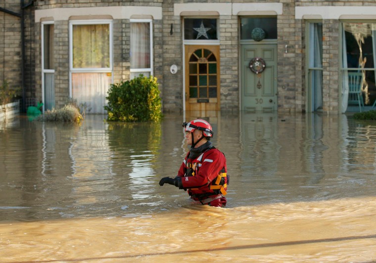 Image: A member of the emergency services navigates a flooded street in York, northern England