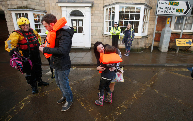 Image: Members of the emergency services rescue a group of people from a flooded street in Tadcaster, northern England