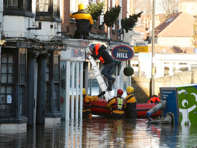 Image: Members of the emergency services rescue a group of people from a flooded street in Tadcaster, northern England