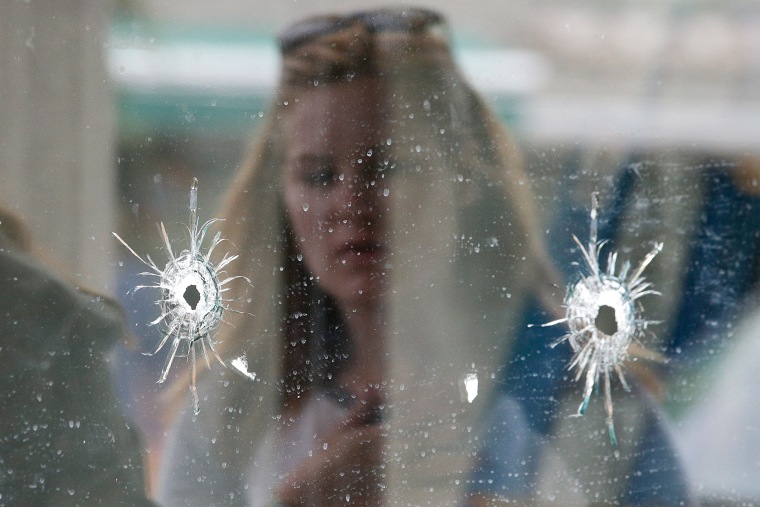 A woman looks at the bullet holes on the window of IV Deli Mark where a mass shooting took place near the University of California, Santa Barbara campus.