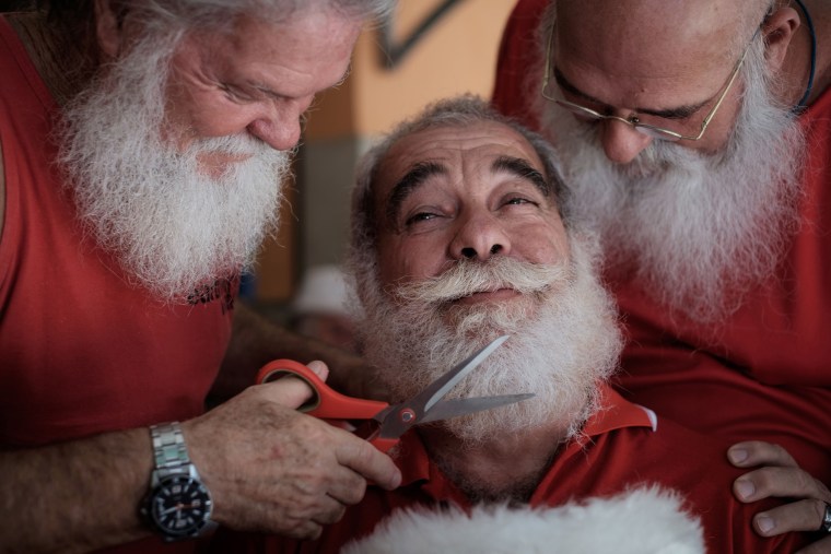 Image: A graduate of the Brazil's School of Santa Claus gets his beard trimmed by students in Rio de Janeiro, Brazil