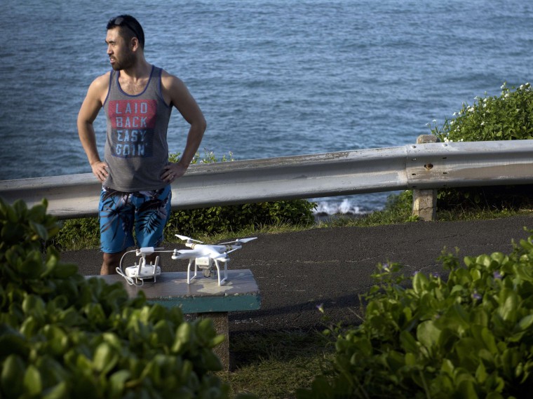Image: A man with a drone stands and watches as a motorcade with U.S. President Barack Obama passes