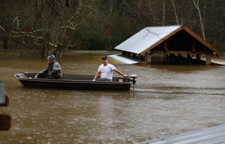 Image: Two men in a boat explore a flooded business nea