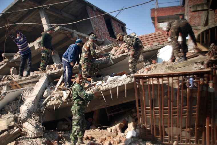 Image: Locals help Indian soldiers remove debris from a damaged building