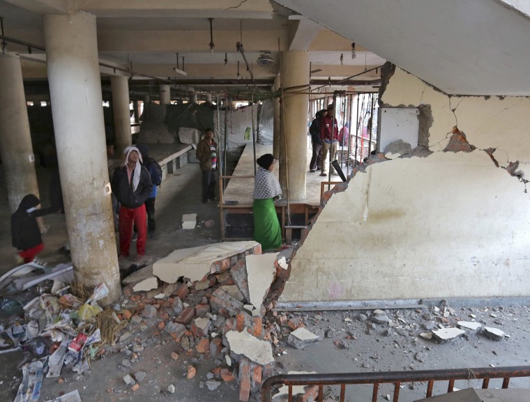 Image: People look at a damaged building at a market place