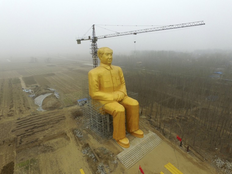 Image: A crane is seen next to a giant statue of Chinese late chairman Mao Zedong under construction near crop fields in a village of Tongxu county, China