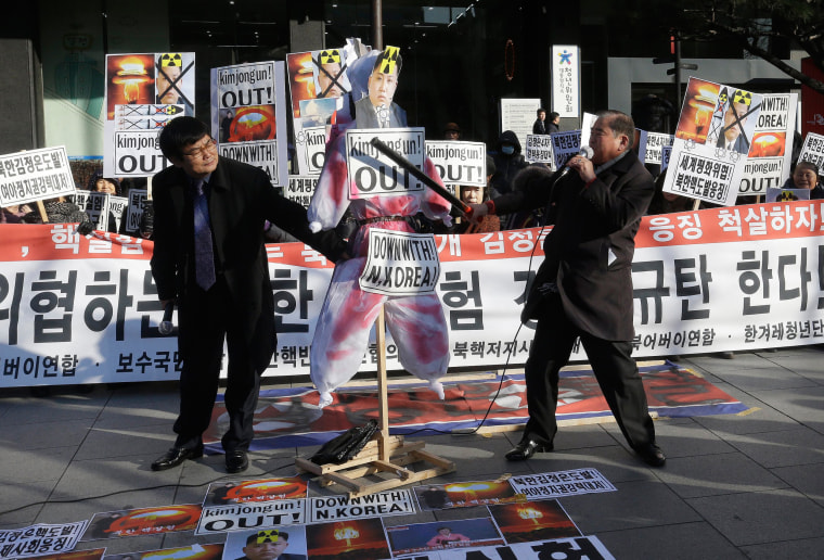 Image: A protester with a wooden stick beats an effigy of North Korean leader Kim Jong Un