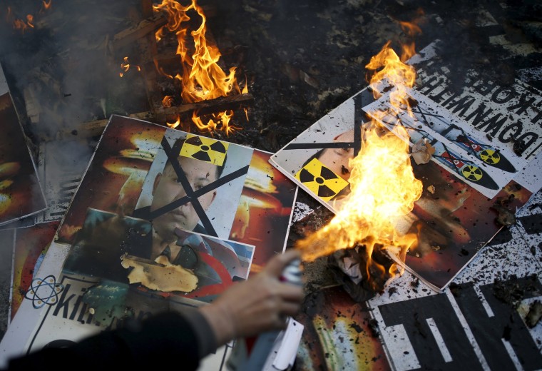 Image: A protester burns banners depicting Kim Jong Un