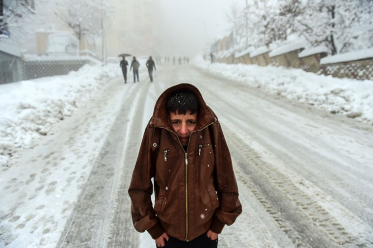Image: A Kurdish boy protects himself against the cold as heavy snow hits the city of Sirnak