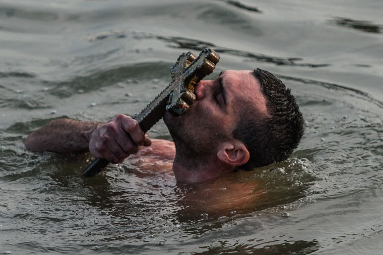 Image: Greek Orthodox swimmer Nicolaos Solis kisses a wooden cross retrieved from the Bosphorus river