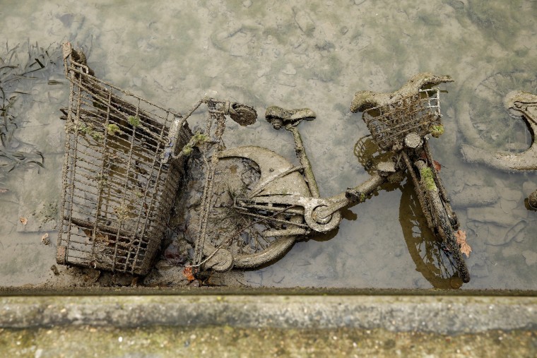 Image: A bicycle and a shopping cart covered with mud appear after the canal Saint-Martin was drained