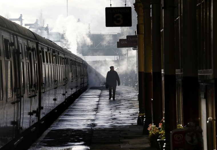 Image: A man walks past the carriages pulled by The Flying Scotsman steam engine at East Lancashire Railway in Bury