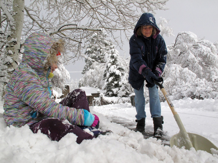Image: A woman shovels snow from the sidewalk outside her homes