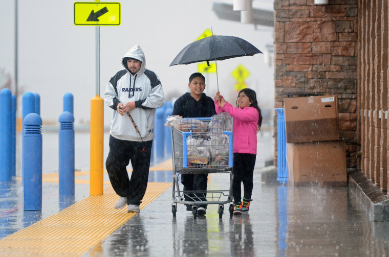 Image: A girl takes tries to cover a shopping cart from rain at Walmart in Hesperia, Calif.