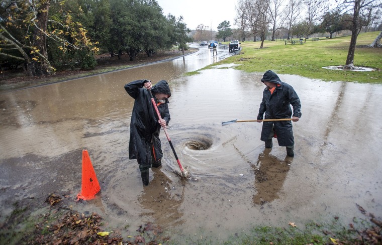 Image: Crews clean out debris from a block drain at Irvine Regional Park in Orange, Calif.