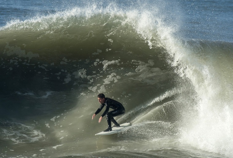 Image: A surfer rides a wave in Seal Beach, Calif.