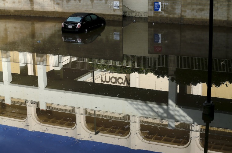 Image: An abandoned car sits in flood waters at a local shopping mall after El Nino-strengthened storm brought rain to San Diego