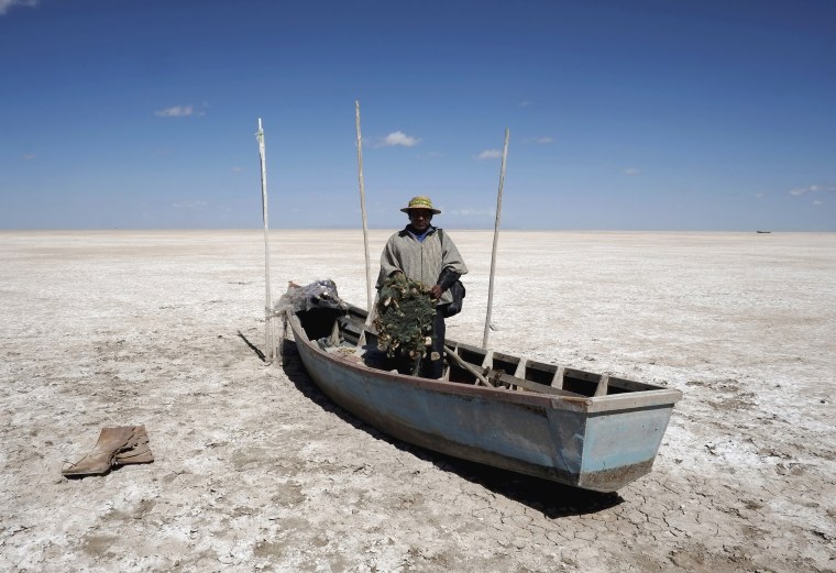 Image: Fisherman Rene Valero, from the Urus ethnic group, is seen on his boat on the dried Poopo lakebed in the Oruro Department, south of La Paz, Bolivia