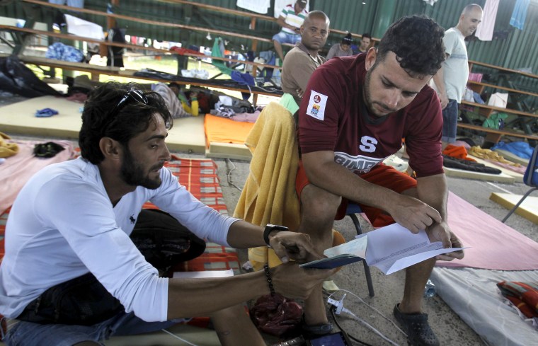 Image: Cuban migrant Ivan Tamayo shows his compatriot Dany Cejas a document which will allow migrants to continue their journey to the Guatemala-Mexico border, at a shelter in La Cruz