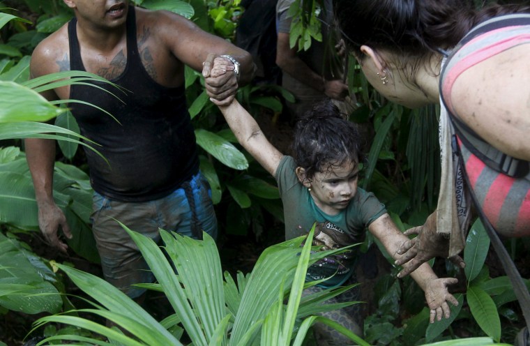 Image: Cuban migrants help a child as they walk down crossing the border from Colombia through the jungle into La Miel, in the province of Guna Yala, Panama