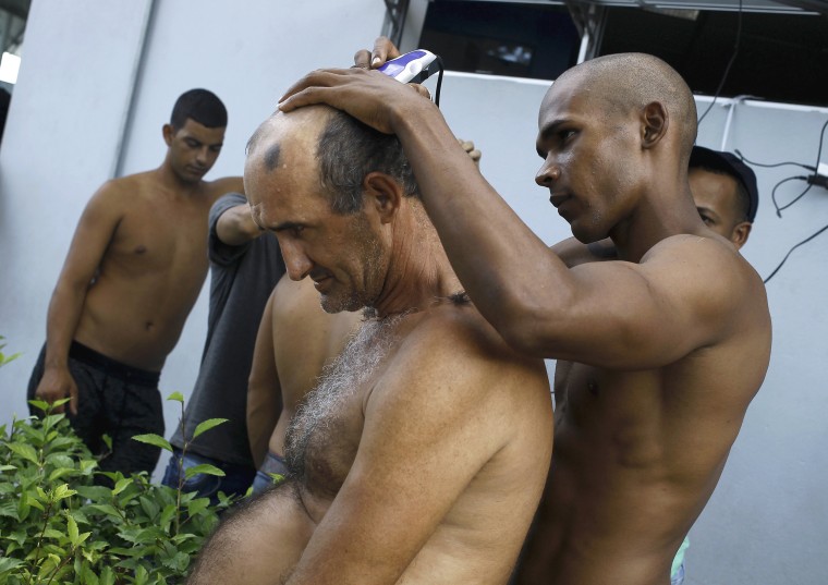 Image: A Cuban migrant cuts the hair of a fellow migrant at the border between Costa Rica and Nicaragua in Penas Blancas