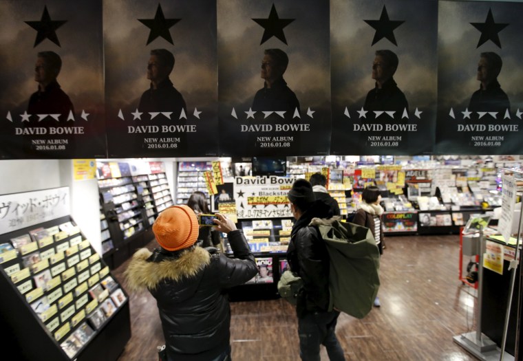 Image: A Japanese fan takes a photo of posters depicting British rock star David Bowie's last album "Blackstar" displayed at a music retailer in Tokyo