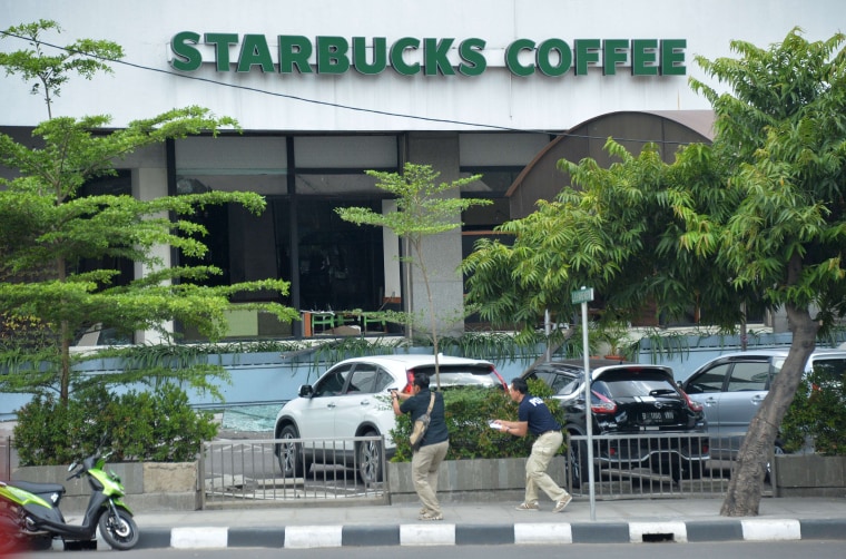 Image: Plainclothes police aim their handguns towards suspects outside a cafe