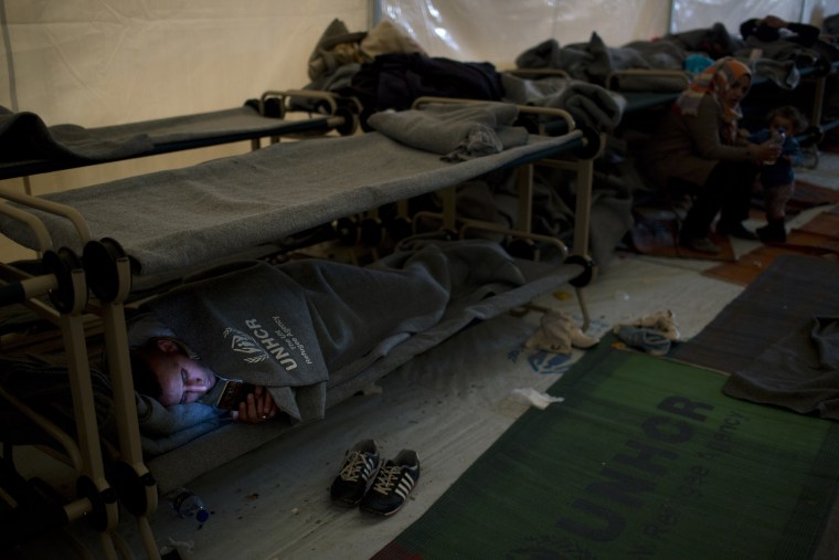 Image: A Syrian man looks on his phone inside the Souda camp in Chios, Greece