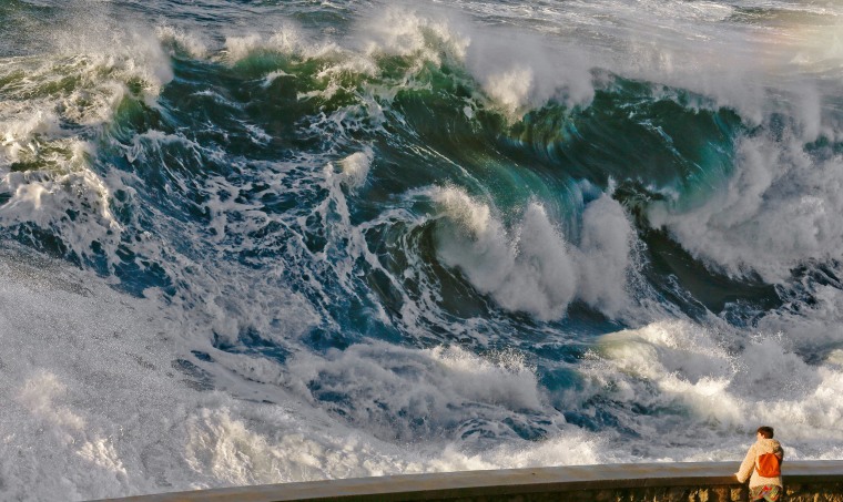 Image: A man watches the huge waves brake at the Paseo Nuevo's promenade