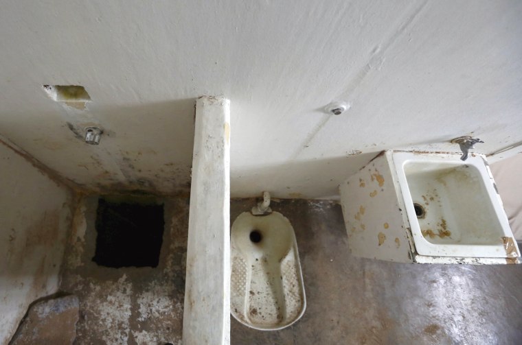 Image: A view of the opening of a tunnel, which is connected to a warehouse, and the toilet area inside Guzman's cell in the Altiplano Federal Penitentiary, where he escaped from, in Almoloya de Juarez