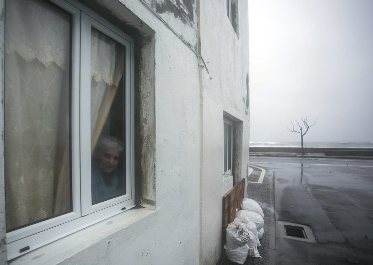 Image: A resident looks out of a window during the passage of hurricane Alex in Ponta Delgada