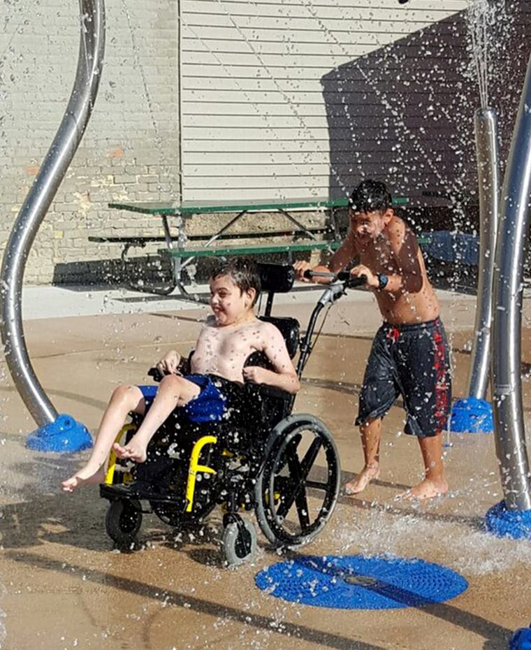 Logan's brother, Leviathan, pushes his wheelchair through a splash pad.