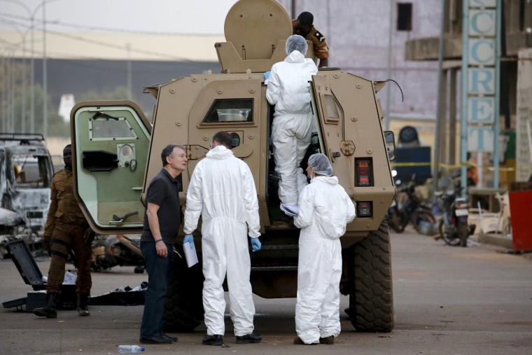 Image: French police (in white) inspect the damage to a Burkinabe armored vehicle