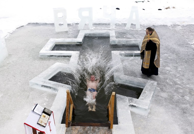 Image: Man dips into the icy waters of a lake as part of celebrations for Orthodox Epiphany on the outskirts of Minsk