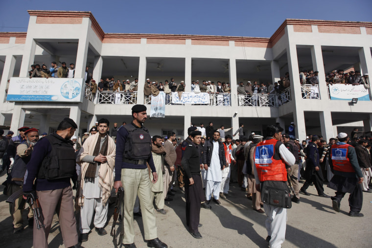 Image: Security officials, rescue workers and relatives gather outside a hospital
