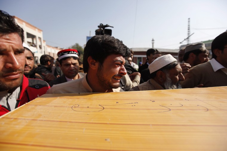 Image: Survivors and rescuers carry the body of a victim