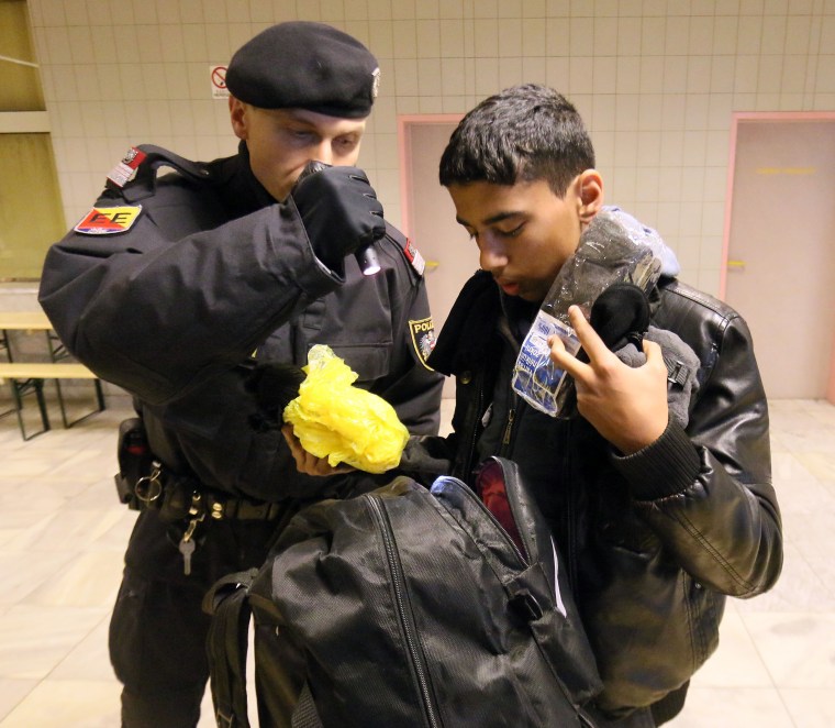 Image: An Austrian police officer checks a migrant arriving from Slovenia.