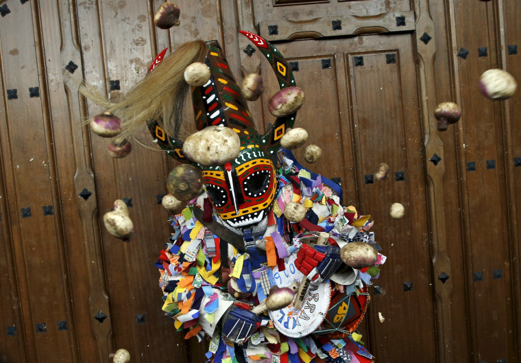 Image: Revellers throw turnips at the Jarramplas, a character who wears a devil-like mask and a colourful costume, as he makes his way through the streets while beating his drum during the Jarramplas traditional festival in Piornal
