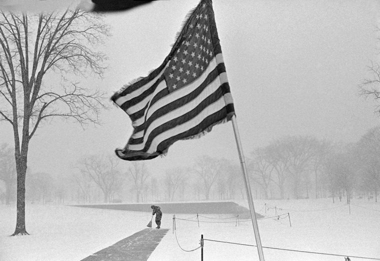 Dale Wey, Cleveland, a Vietnam veteran, sweeps the walkway in front of the Vietnam Veterans Memorial during a snowstorm in Washington on Friday, Feb. 11, 1983. Wey is part of a group of veterans standing vigil at the memorial.