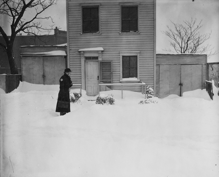 Above, a person stands in front of a house after snow piled up in February, 1936.