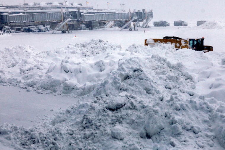 A snow plow is dwarfed by a pile of snow during snow cleanup on the tarmac at Washington's Reagan National Airport, Saturday, Feb. 6, 2010, as a massive snow storm has hit the Washington area, canceling all flights for Saturday.