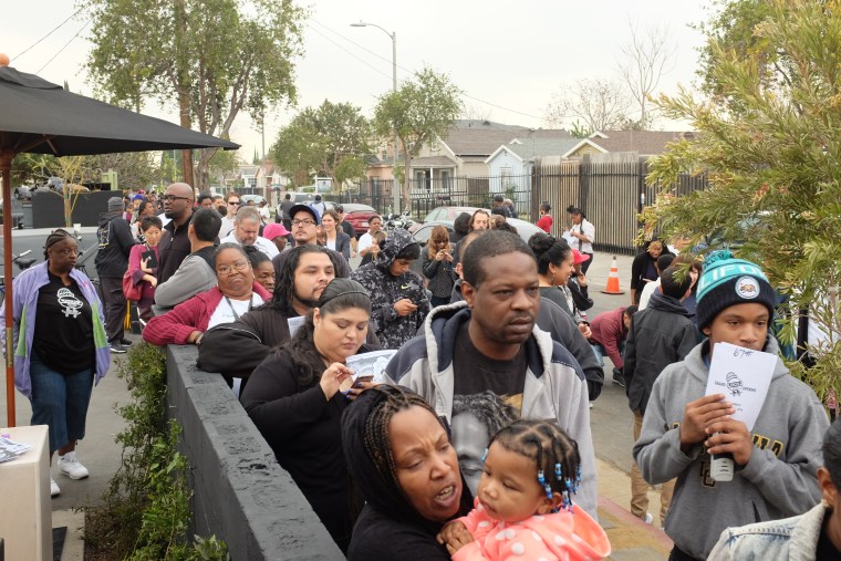 Hundreds of people wait to enter LocoL near the corner of Anzac Avenue and East 103rd Street in Watts, Los Angeles.