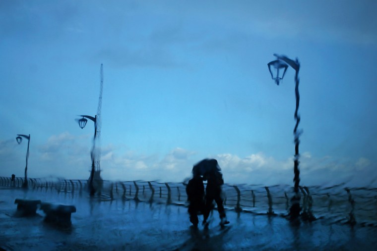 Image: A couple stands under an umbrella to shield themselves from heavy rain